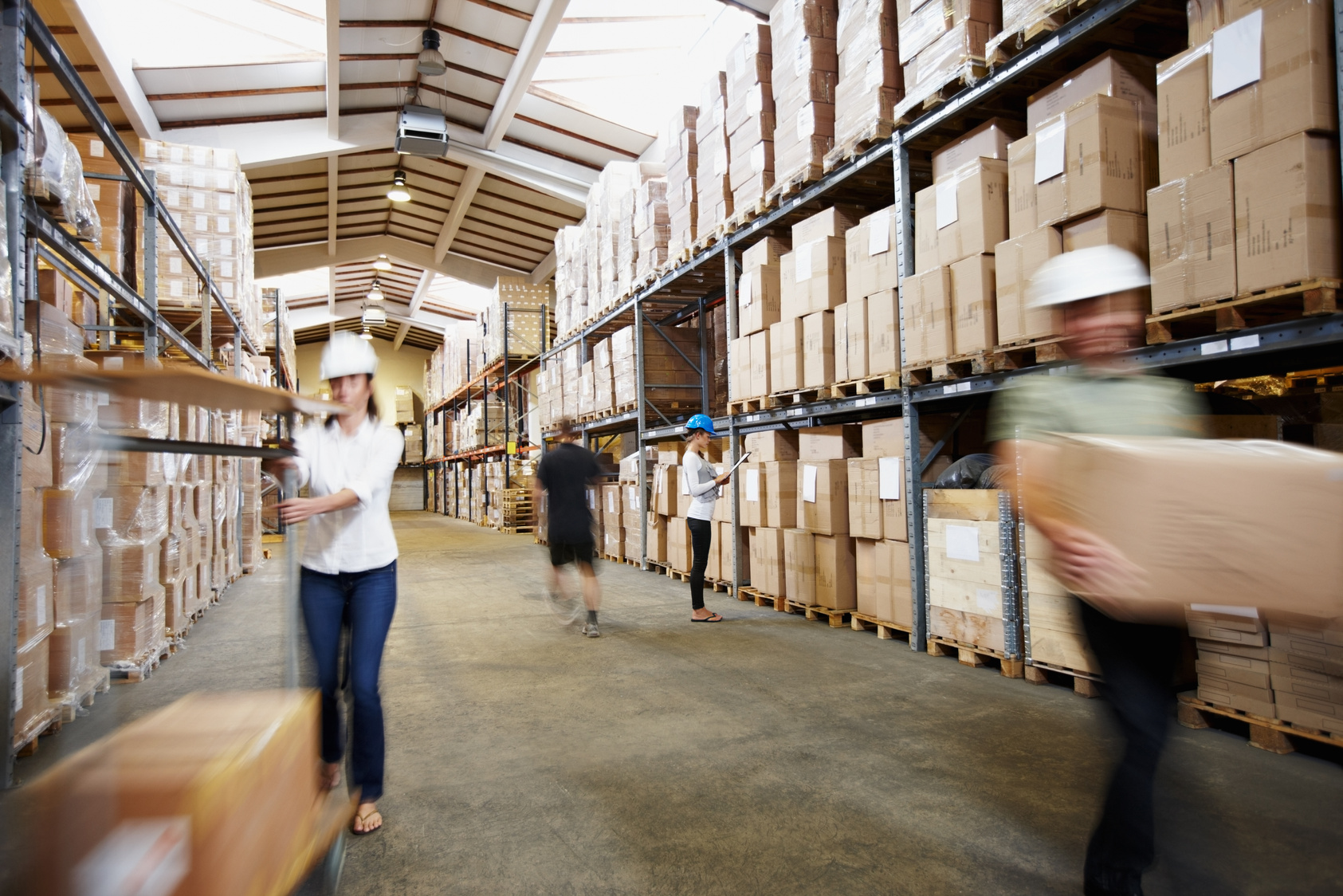 Workers at the wholesale warehouse with arrangement of goods