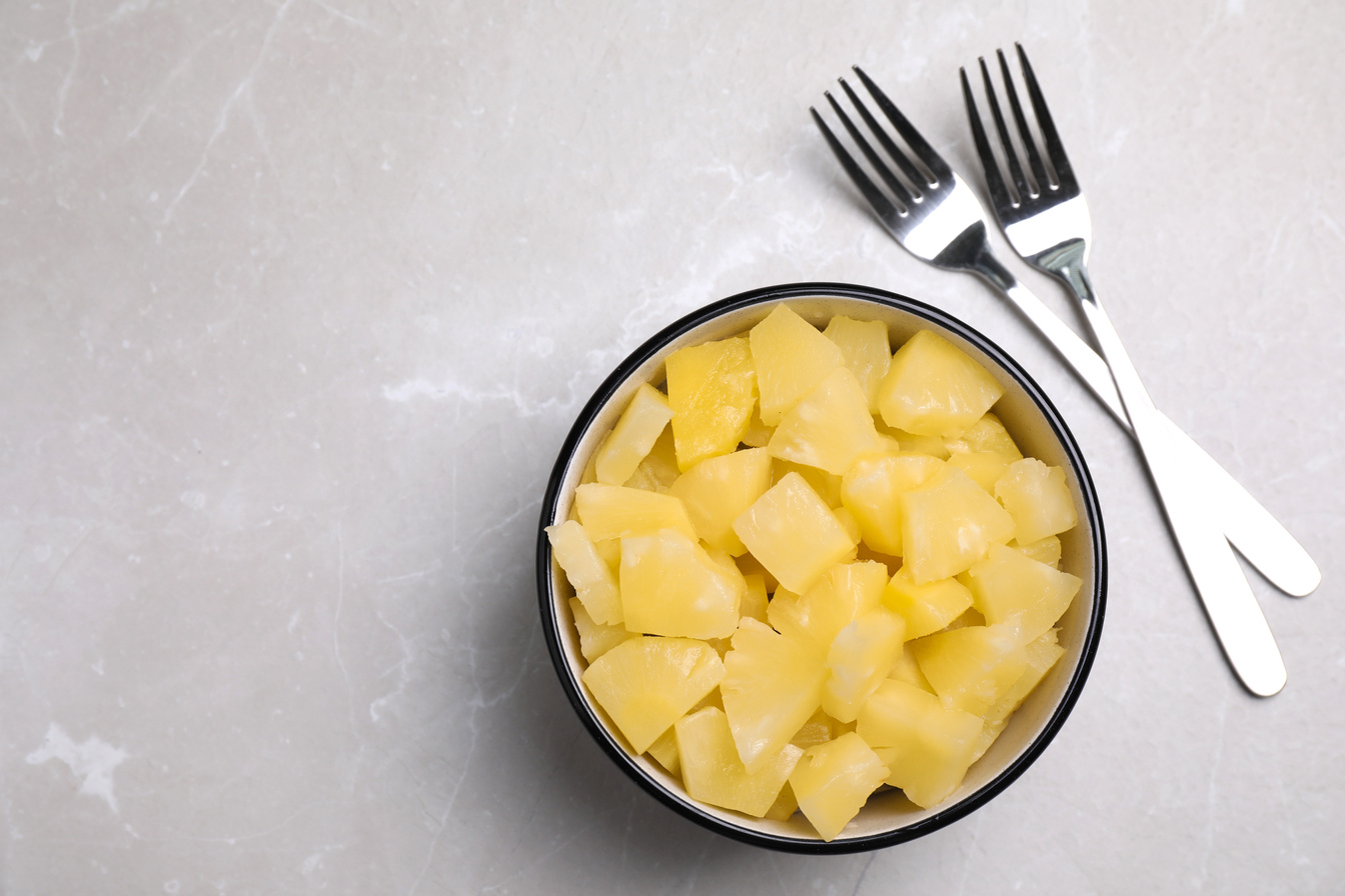 Tasty Canned Pineapple Pieces and Forks on Light Grey Marble Tab